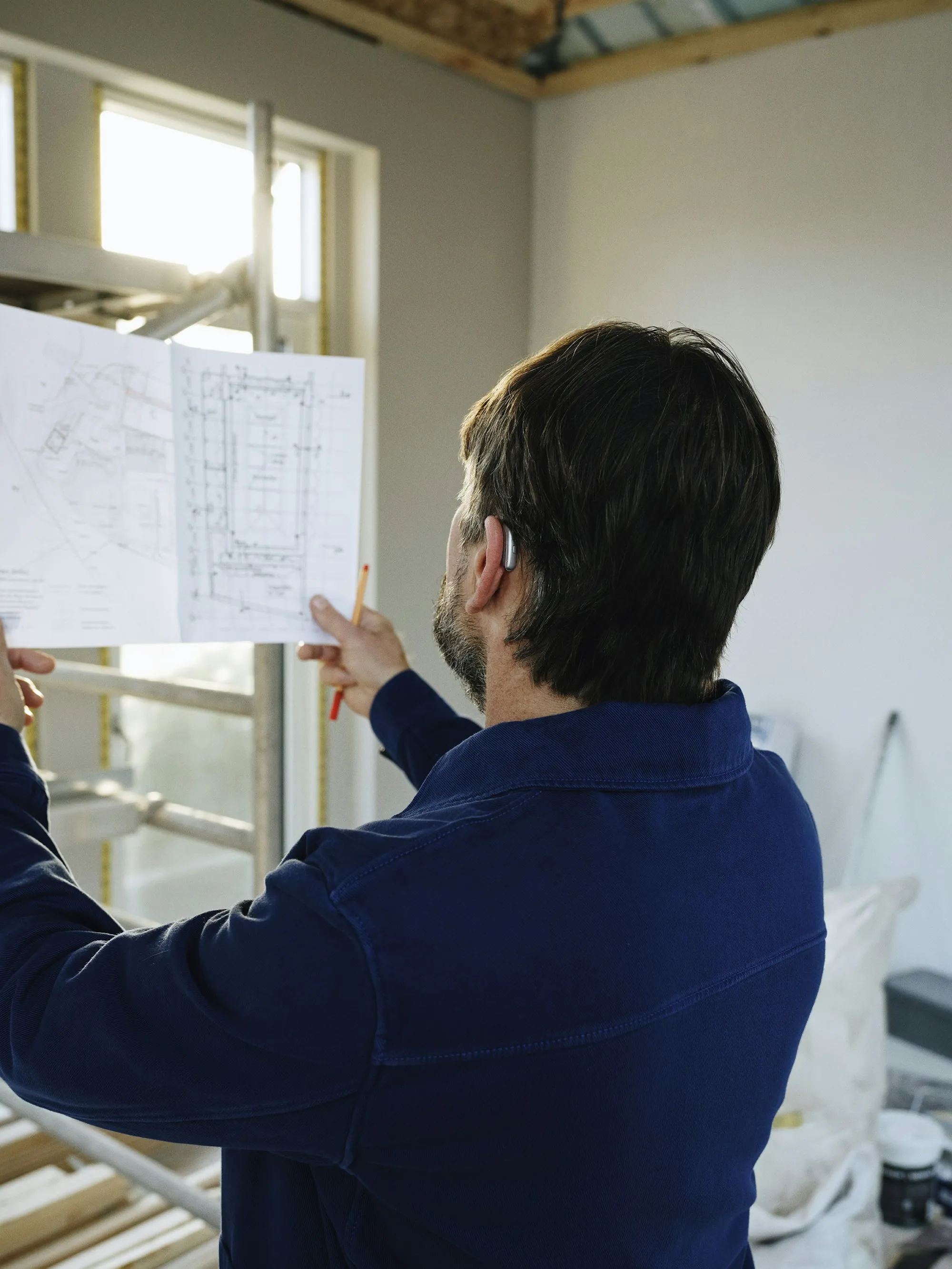 Builder reviewing floor plans inside a home under construction